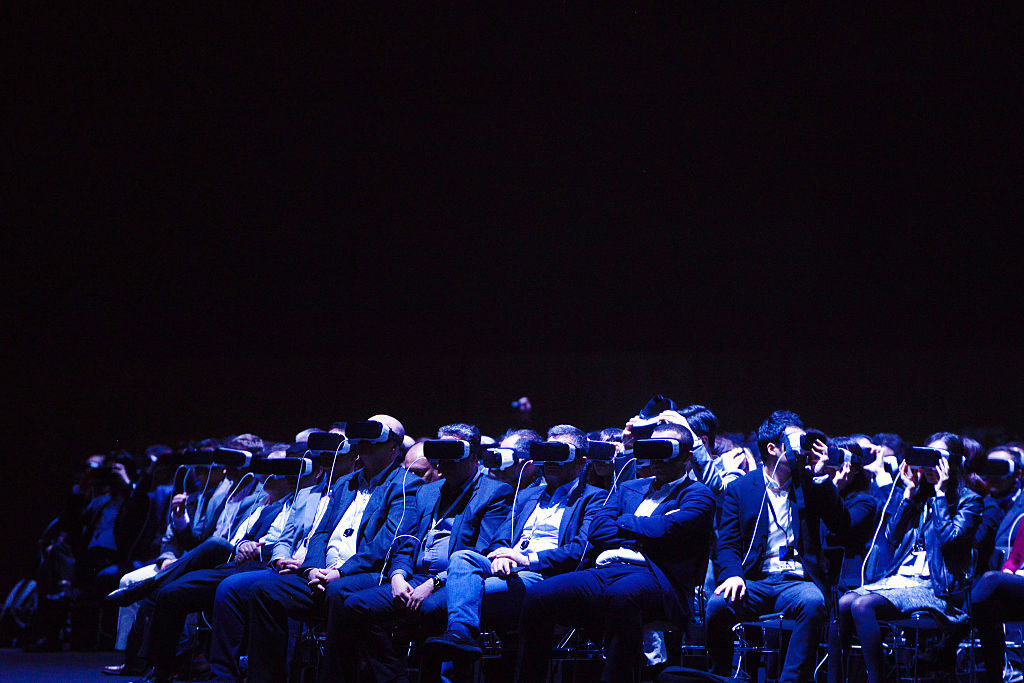 A group of people with VR headsets sit in what resembles a black void