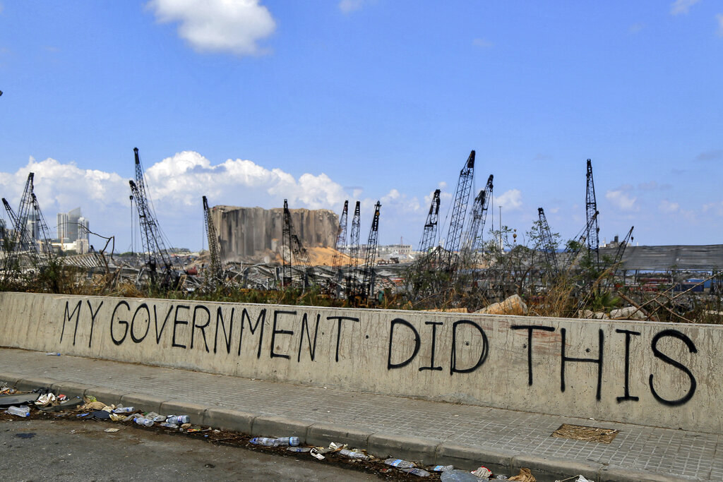 A graffitied barricade reads &#x27;my government did this&#x27; in front of miles of desolation and trash