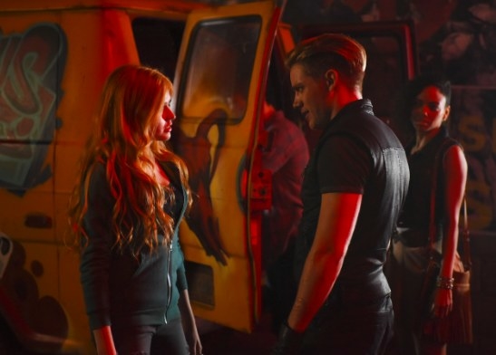 Clary and Jace look at each other while standing in front of a van