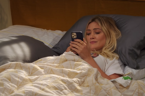Sophie laying in bed on her phone