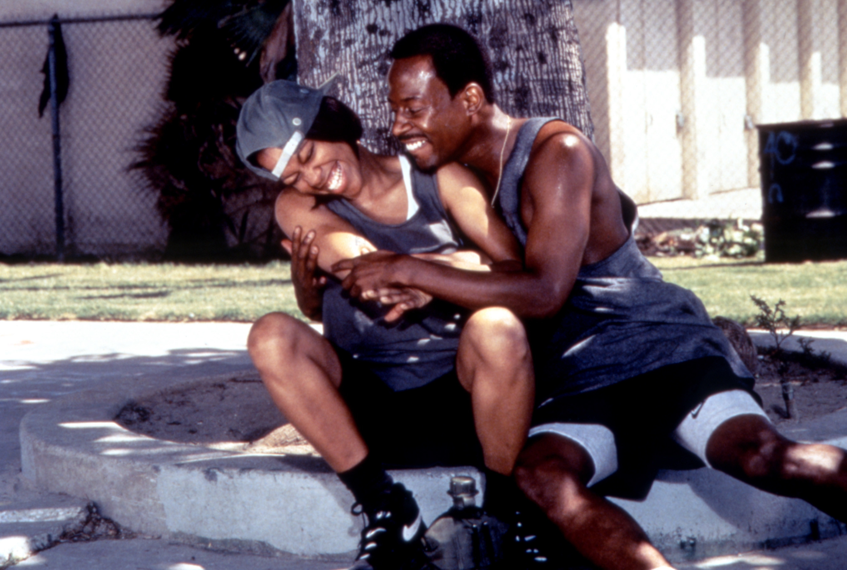 A Black couple embraces each other while sitting underneath a tree