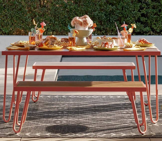 Two benches and a table with wood top and red metal legs