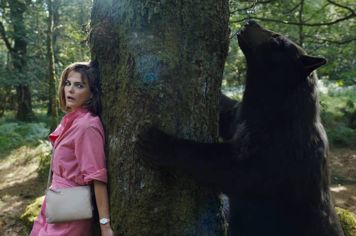keri russell hides from a bear behind a tree in the woods