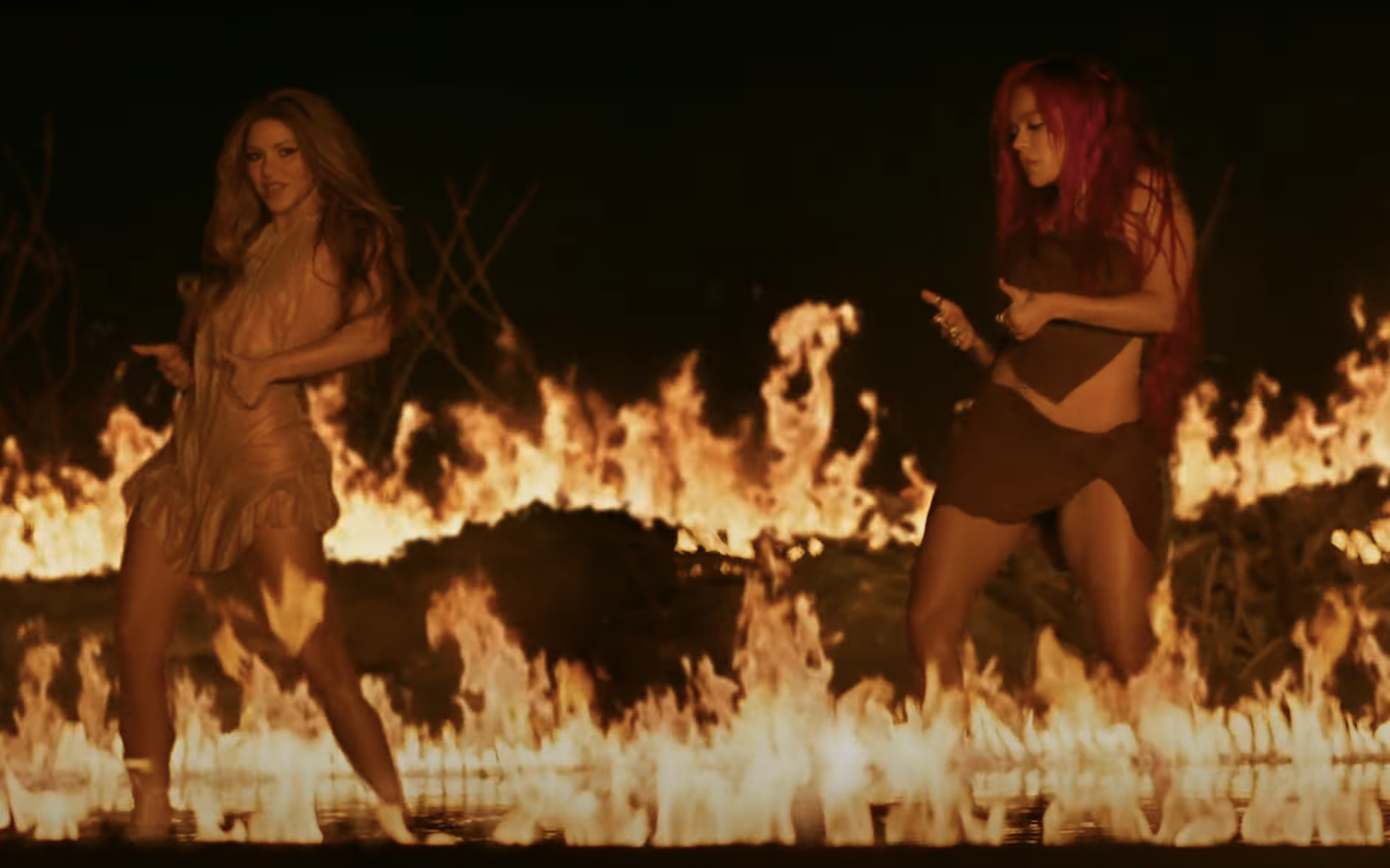 Screenshot of Shakira and Karol from the video, with flames behind them