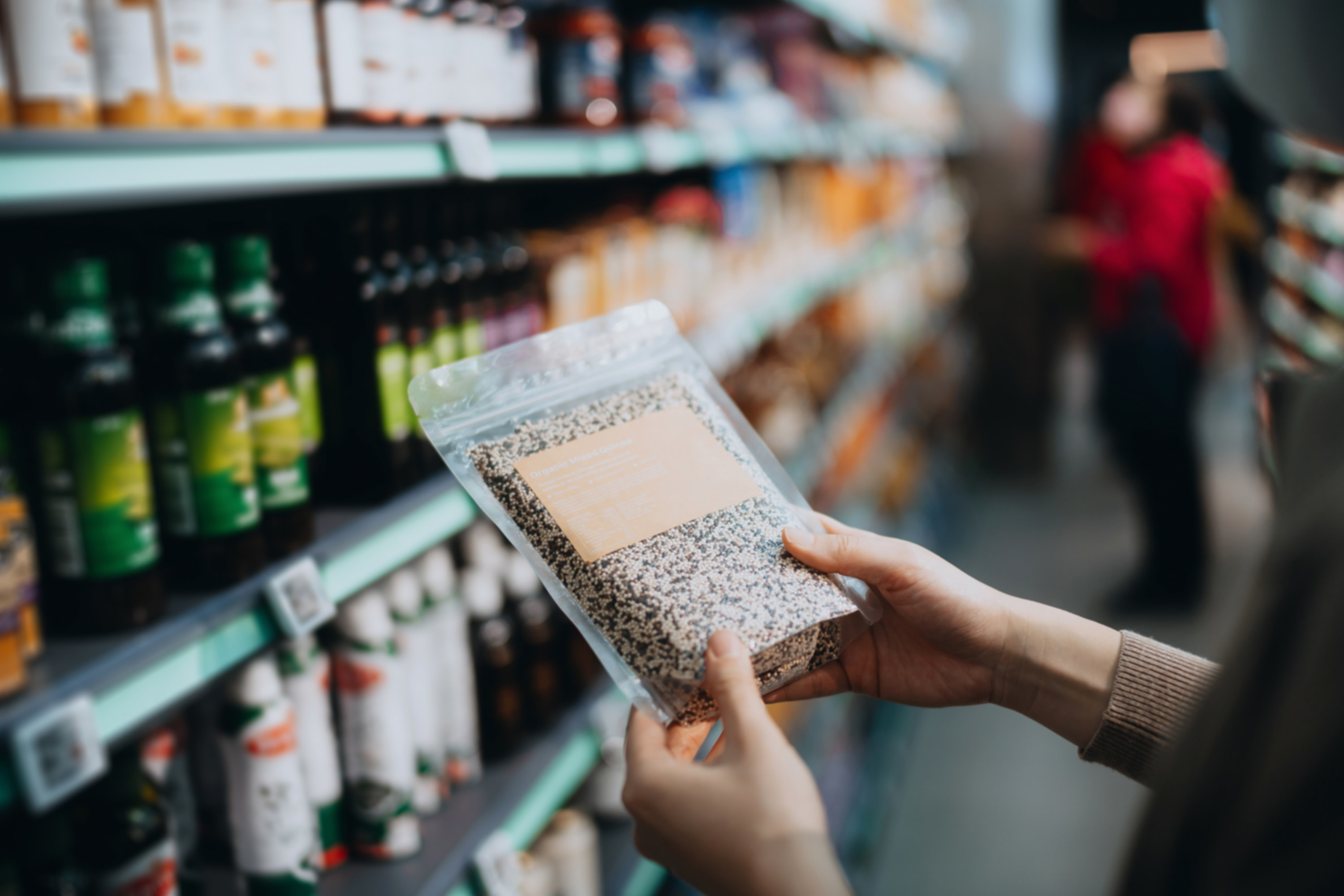 woman holds bag of quinoa in super market