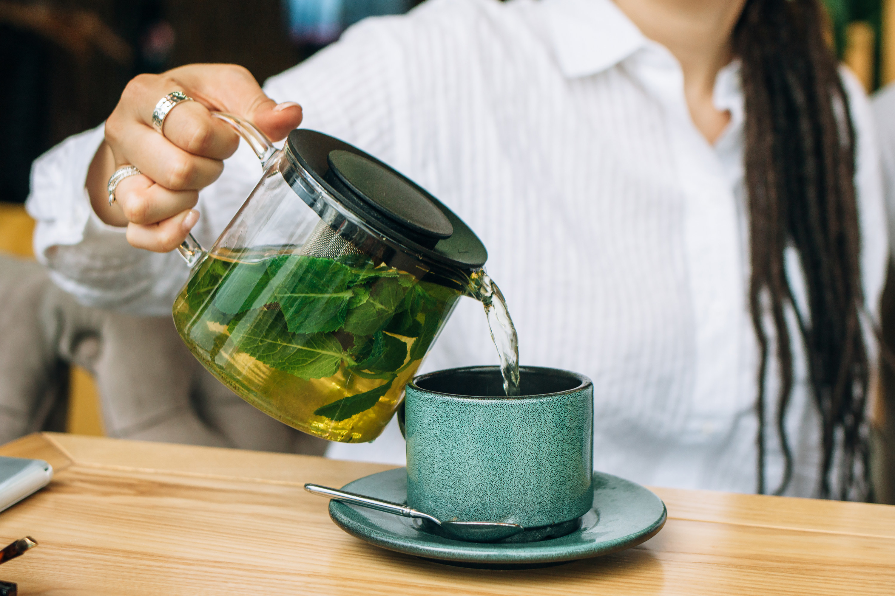 woman pours green tea into a mug