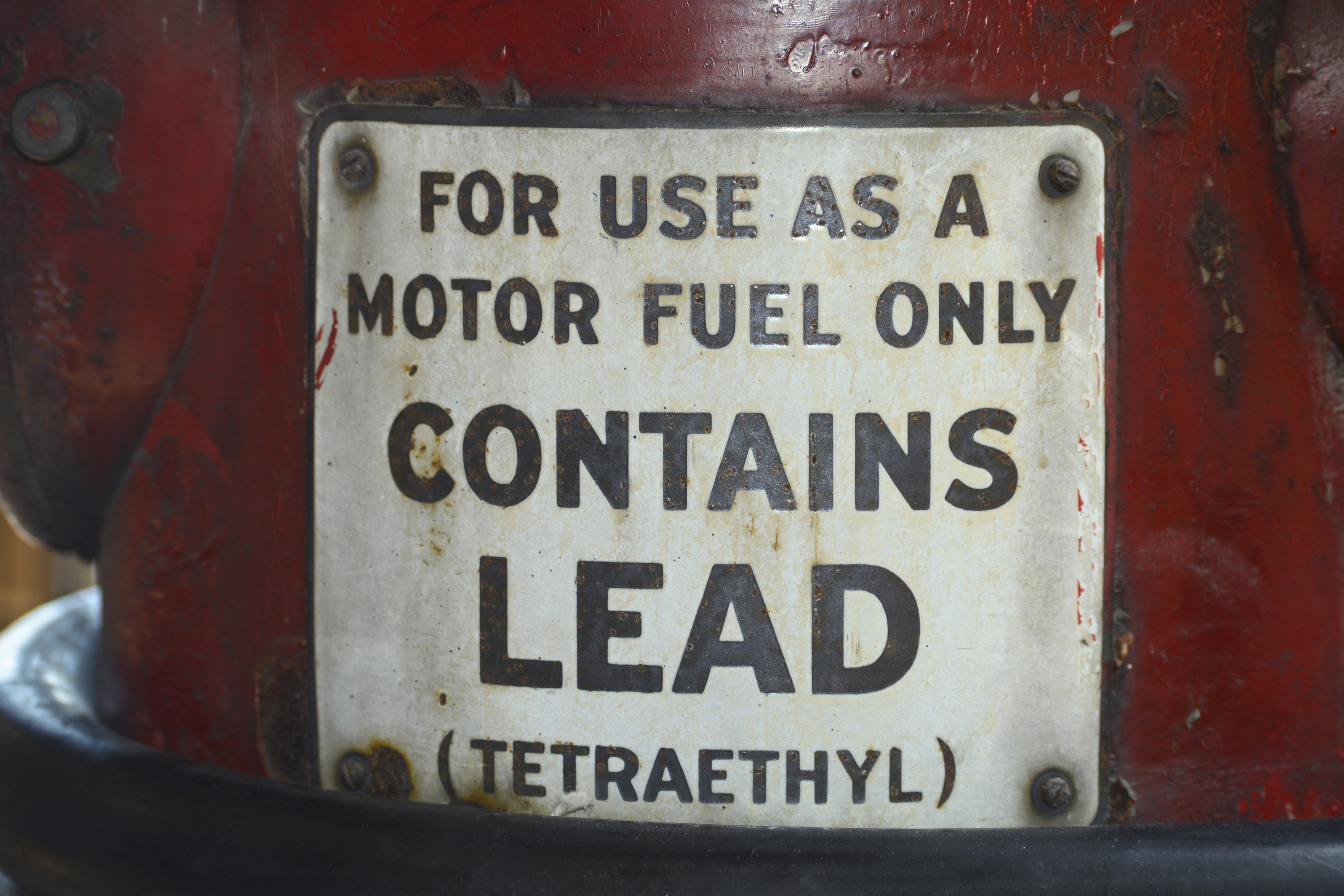 A sign on a vintage gasoline pump advises that the gas contains lead