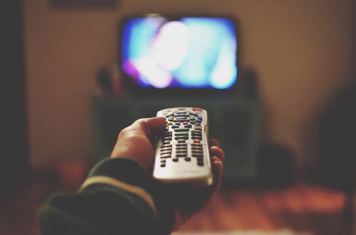 Someone watching TV and holding a remote