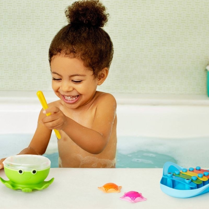 Child plays with a drum in the bath