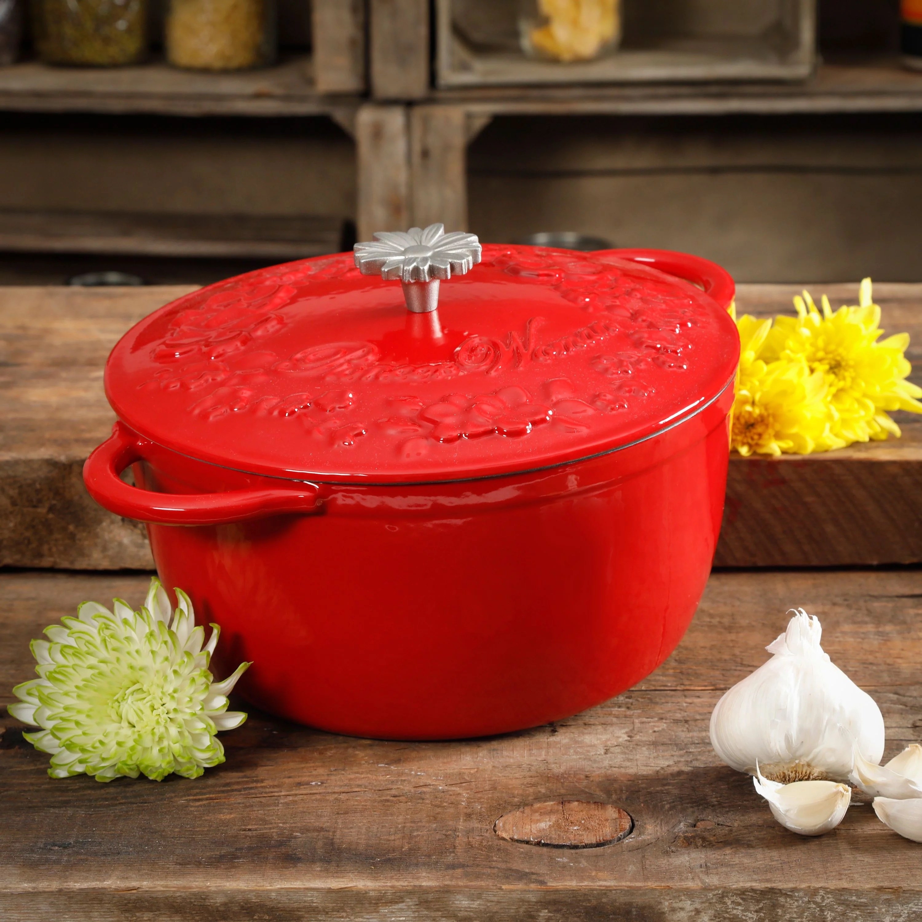a red dutch oven sitting on a table next to a head of garlic