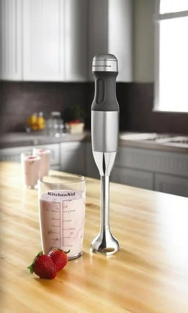 a wireless silver emersion blender with a metal top on a kitchen counter next to a smoothie