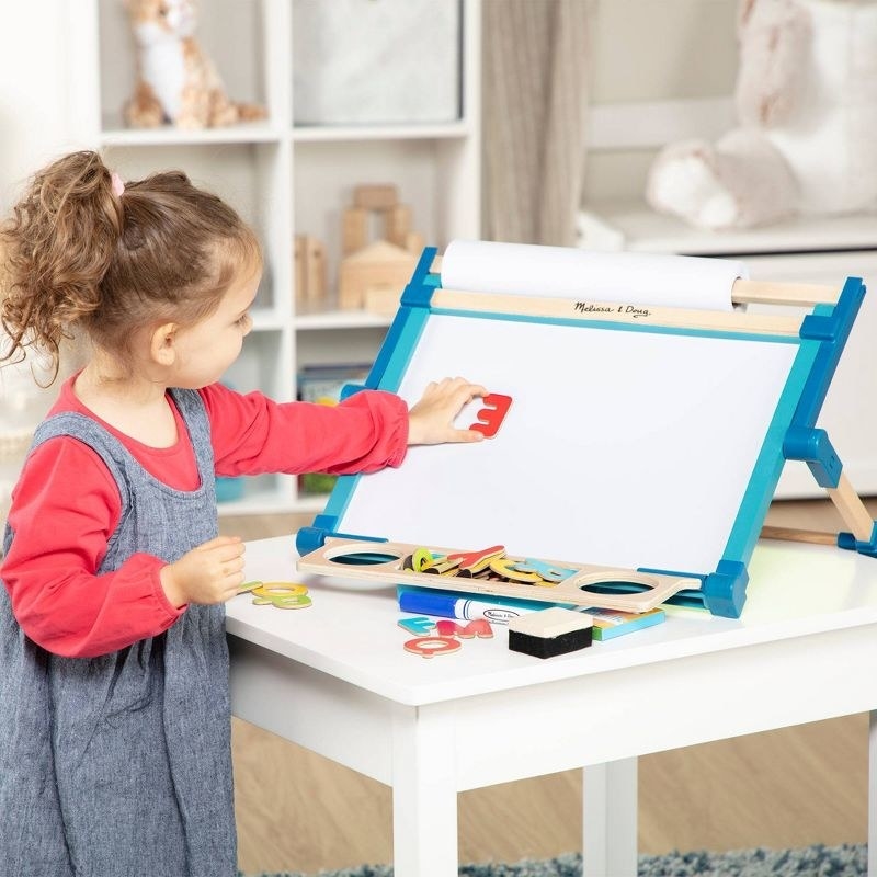 Child plays with easel magnets