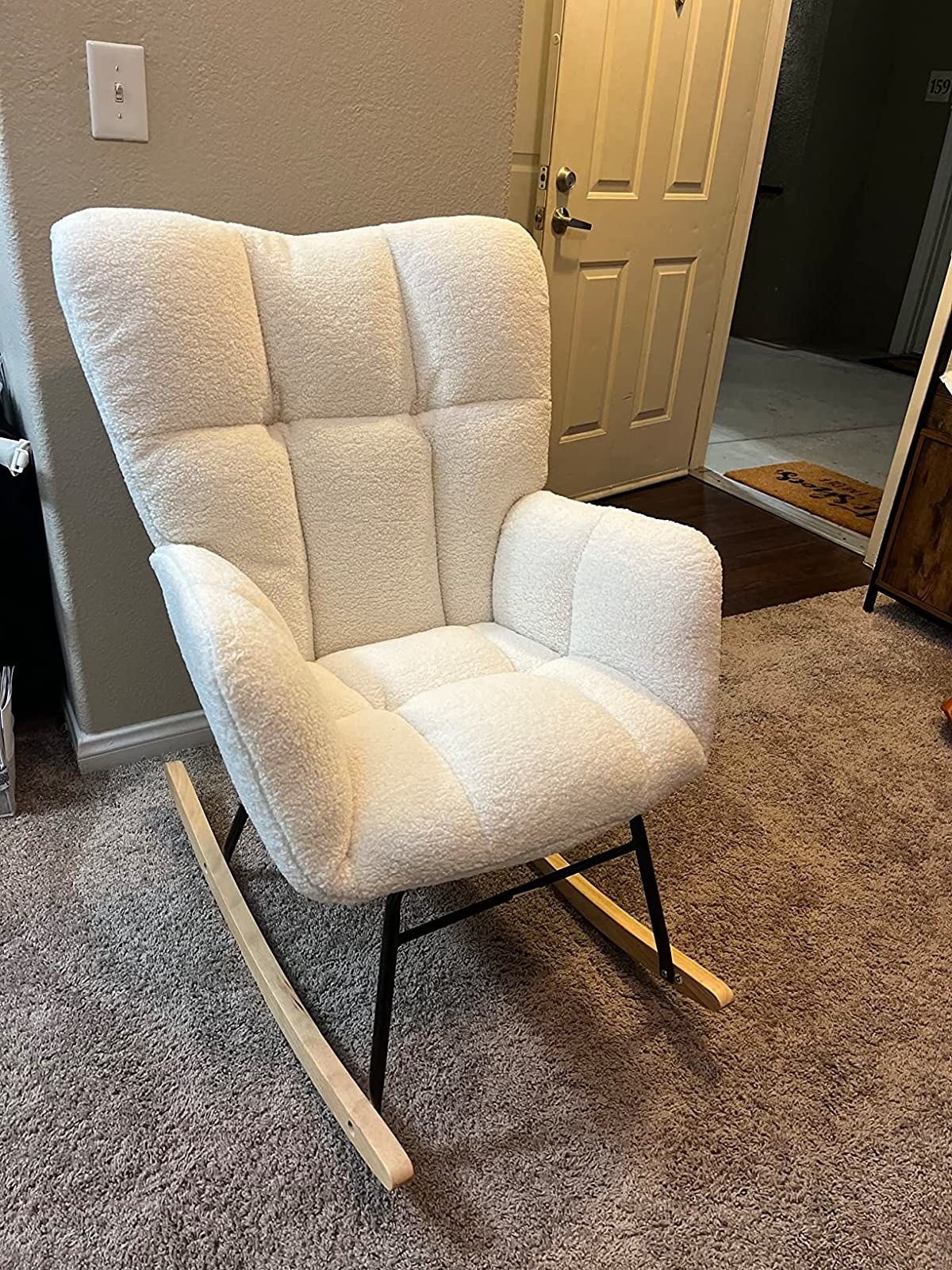 a reviewer photo of the white fuzzy rocking chair on carpet