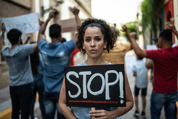 Mid adult protester woman holding a sign outdoors