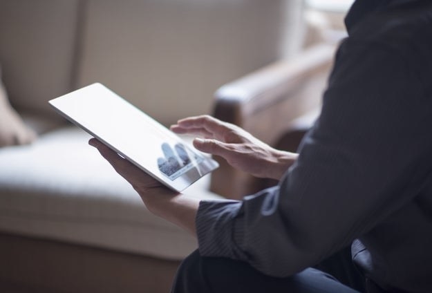 A man uses a digital tablet while sitting on a couch