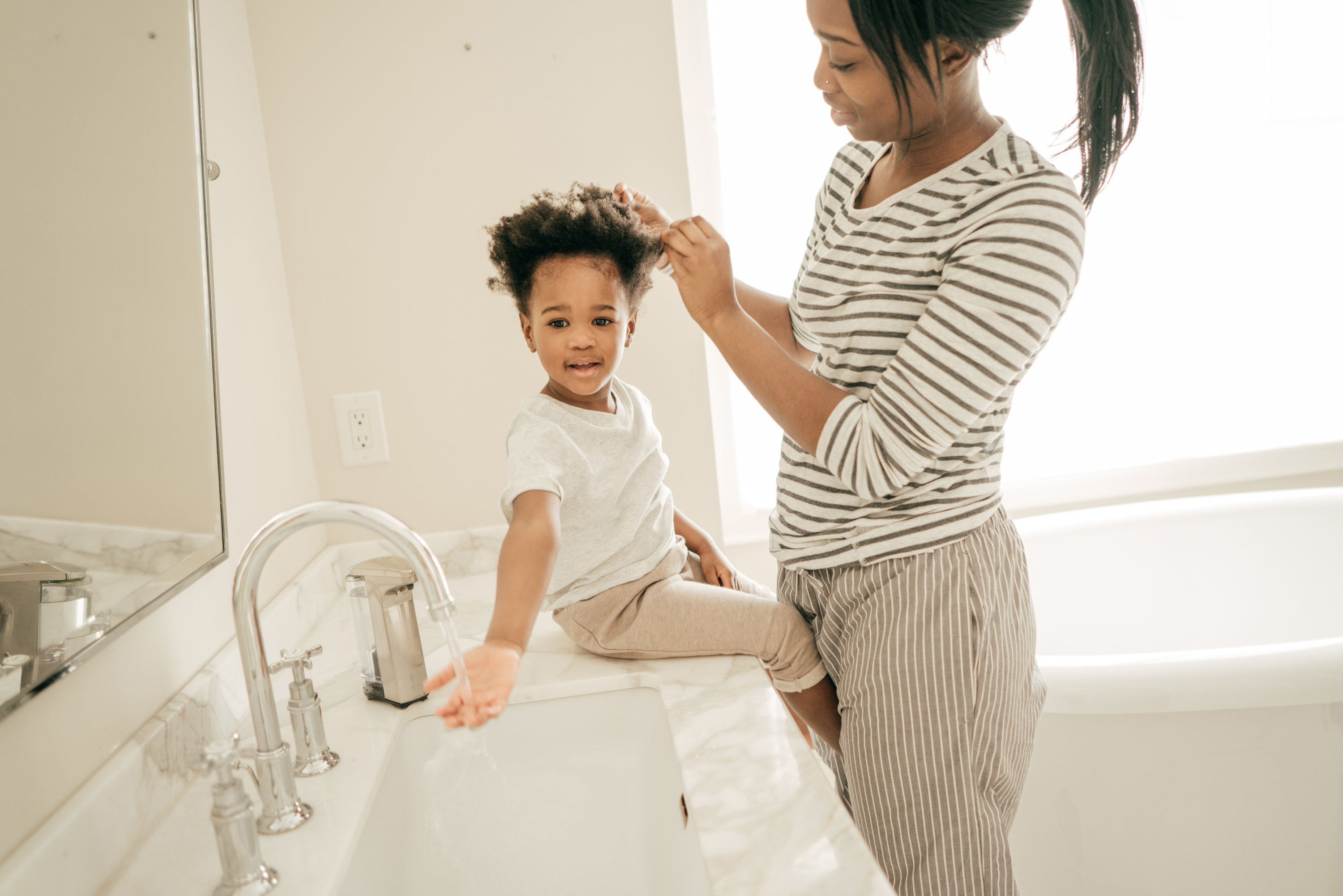 mom doing her baby&#x27;s hair in the bathroom