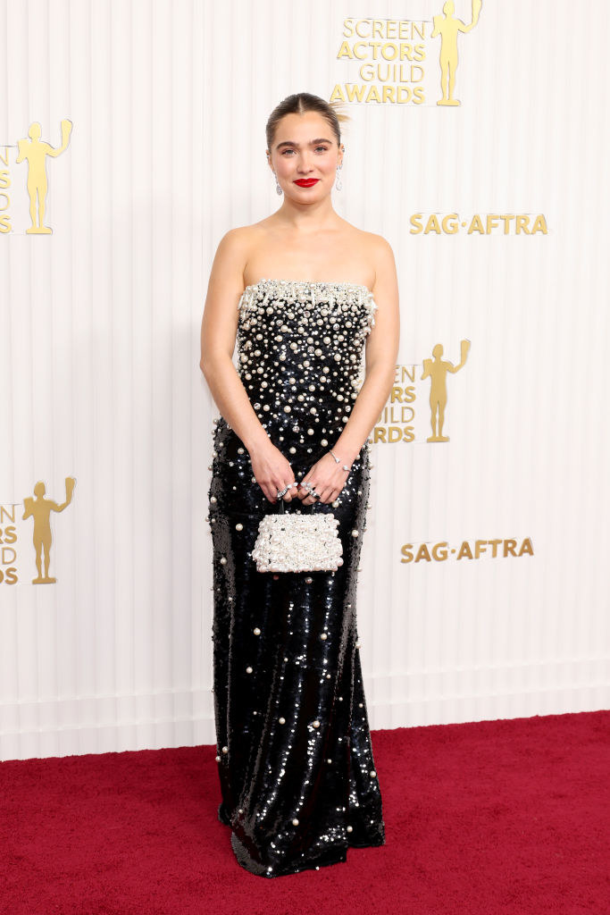 Haley Lu Richardson wearing a form-fitting sequined gown with pearl embellishments, accompanied by a pearl purse