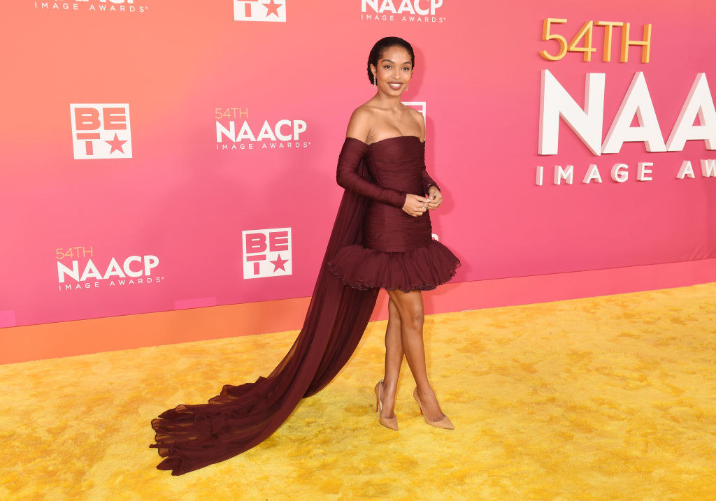Yara in a strapless short dress with ruffled bottom and off-the-shoulder train