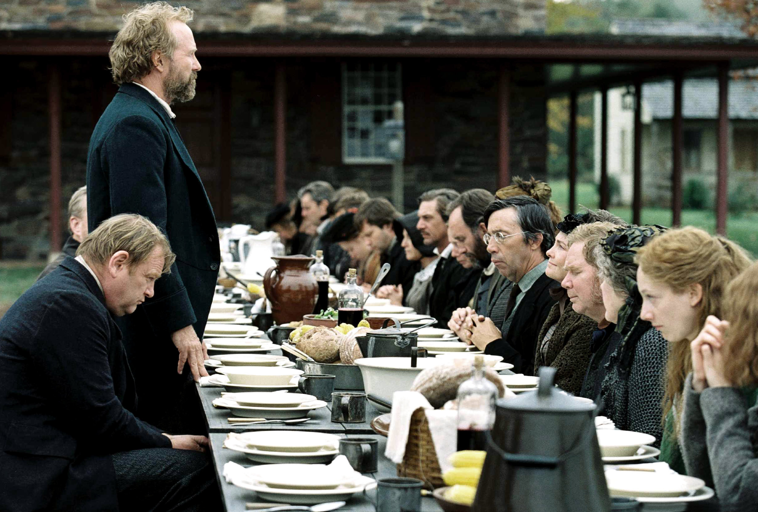 William Hurt prays before a long table of people