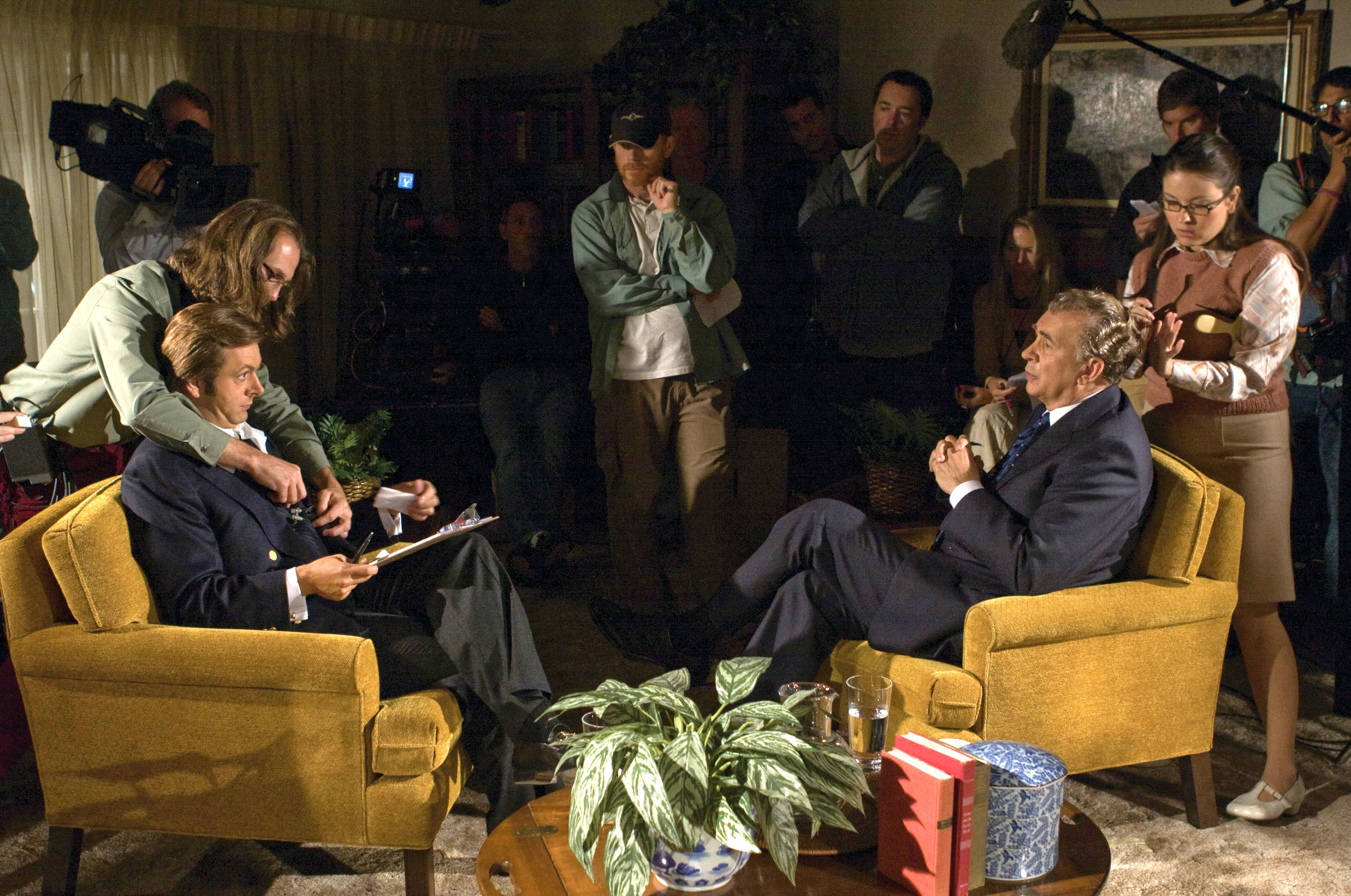 Michael Sheen and Frank Langella sit in chairs preparing for an interview