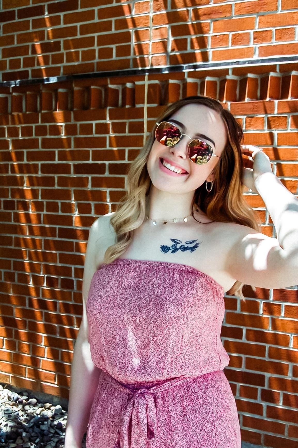 reviewer posing in front of brick wall in pink polarized sunglasses