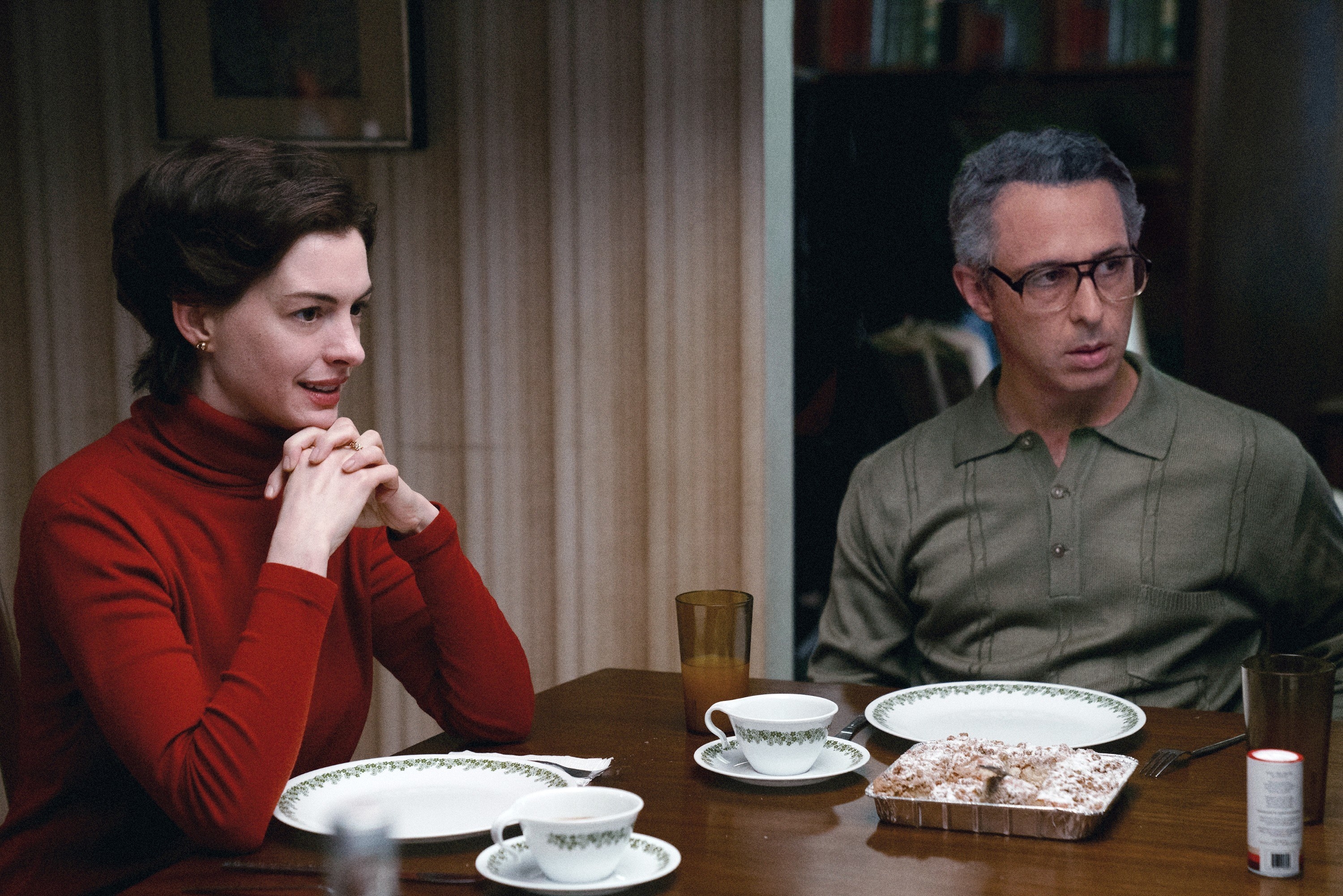 Anne Hathaway and Jeremy Strong sit at a dining room table