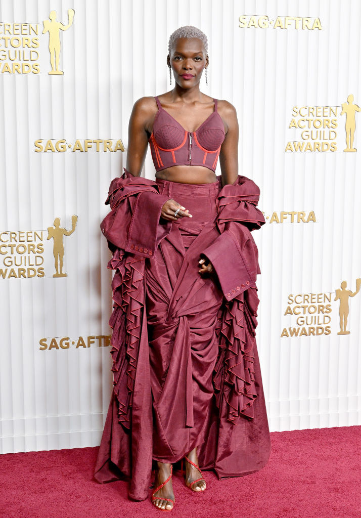 Sheila on the red carpet in a corseted bra top and a ruffled skirt gown with cape sleeves