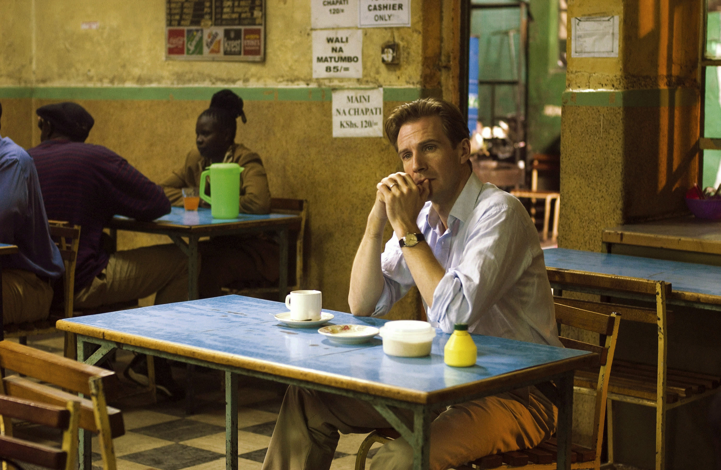 Ralph Fiennes sits at a table