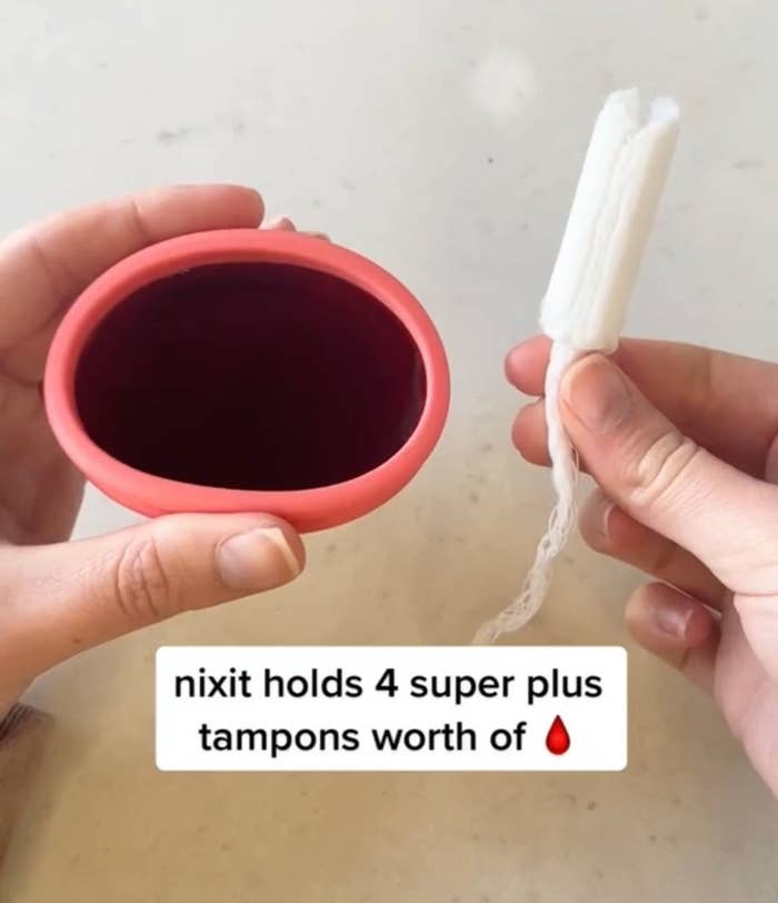 A person holding up the cup and tampon