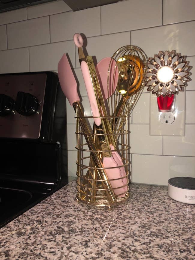 reviewer image of the pink and gold utensils in their gold-colored holder
