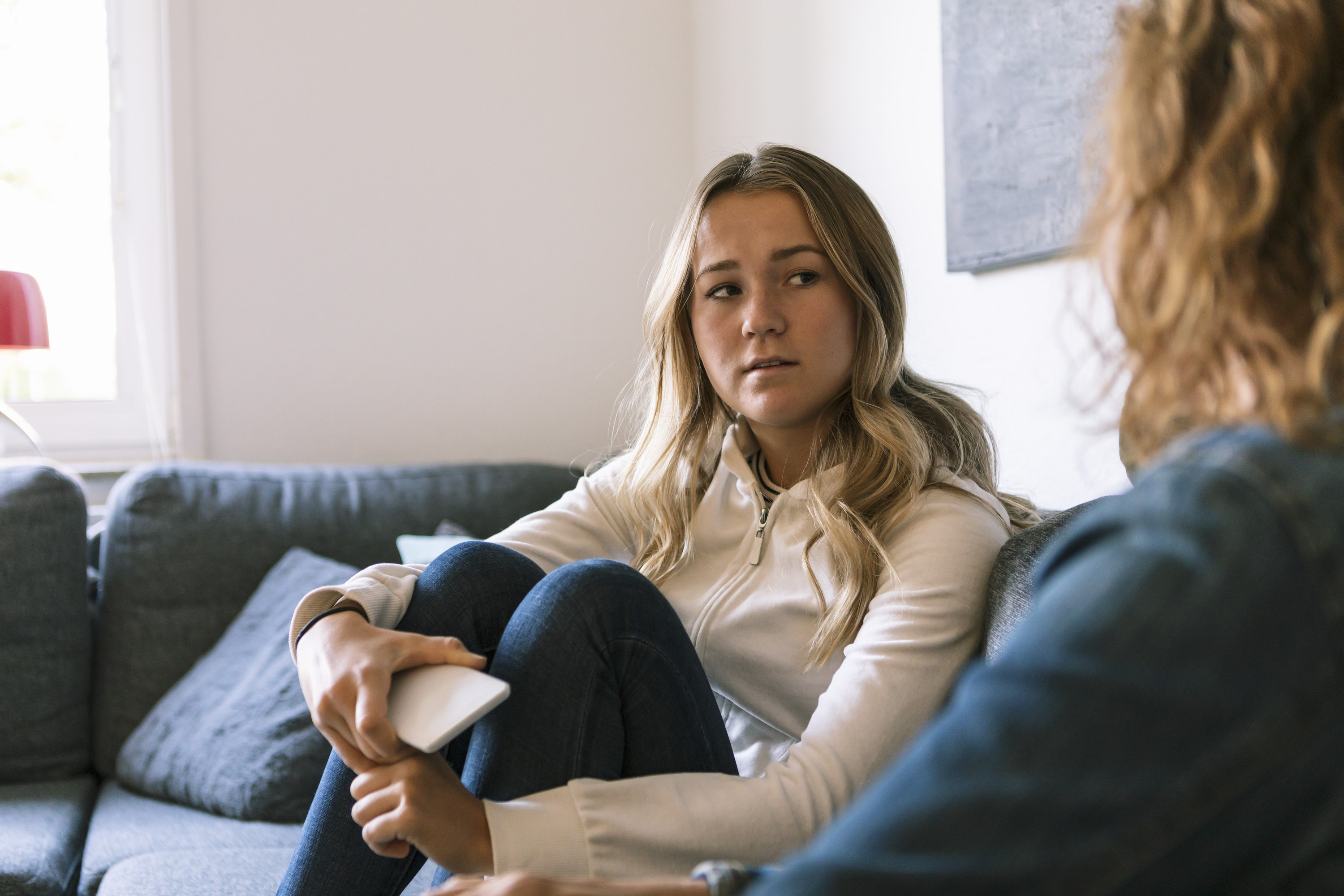 a mom and a daughter talking on a couch