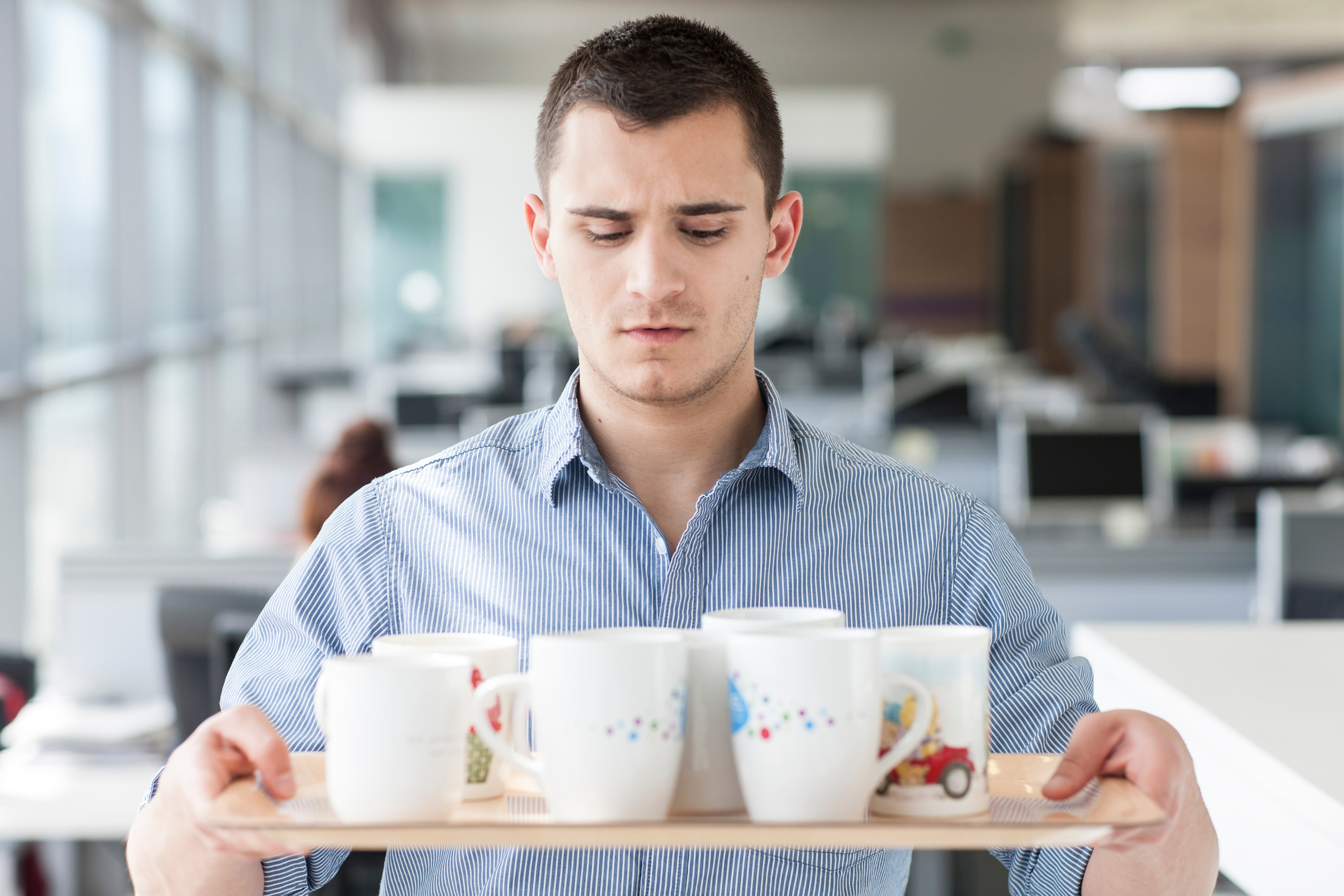 intern unhappily carries mugs