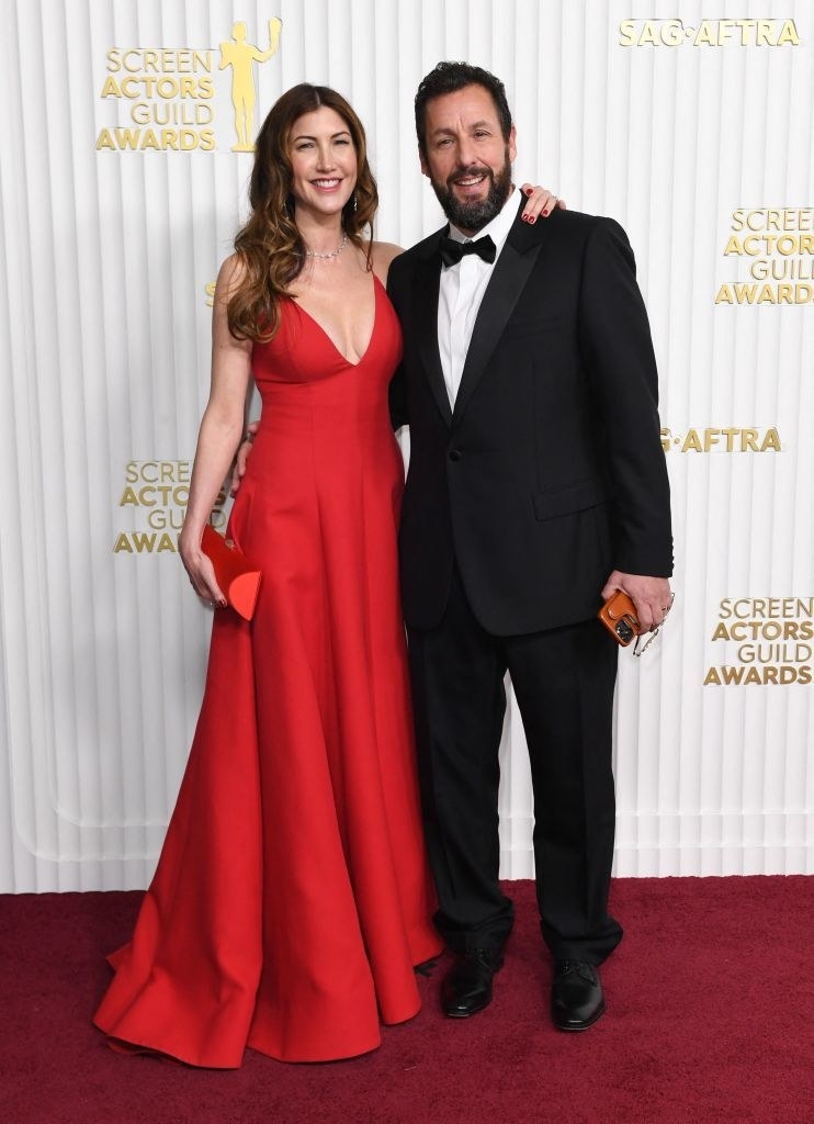 Adam Sandler and his wife, Jackie Sandler, smiling and arm in arm on the red carpet for the 29th Screen Actors Guild Awards