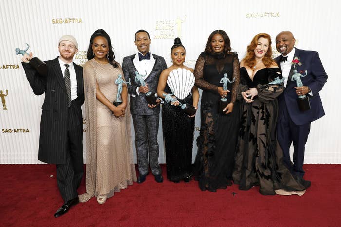 The cast of Abbot Elementary pose on the red carpet with their awards