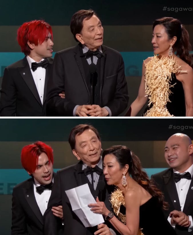 James Hong and Michelle Yeoh speaking on stage while accepting the award for Ensemble Cast in a Motion Picture for Everything Everywhere All At Once