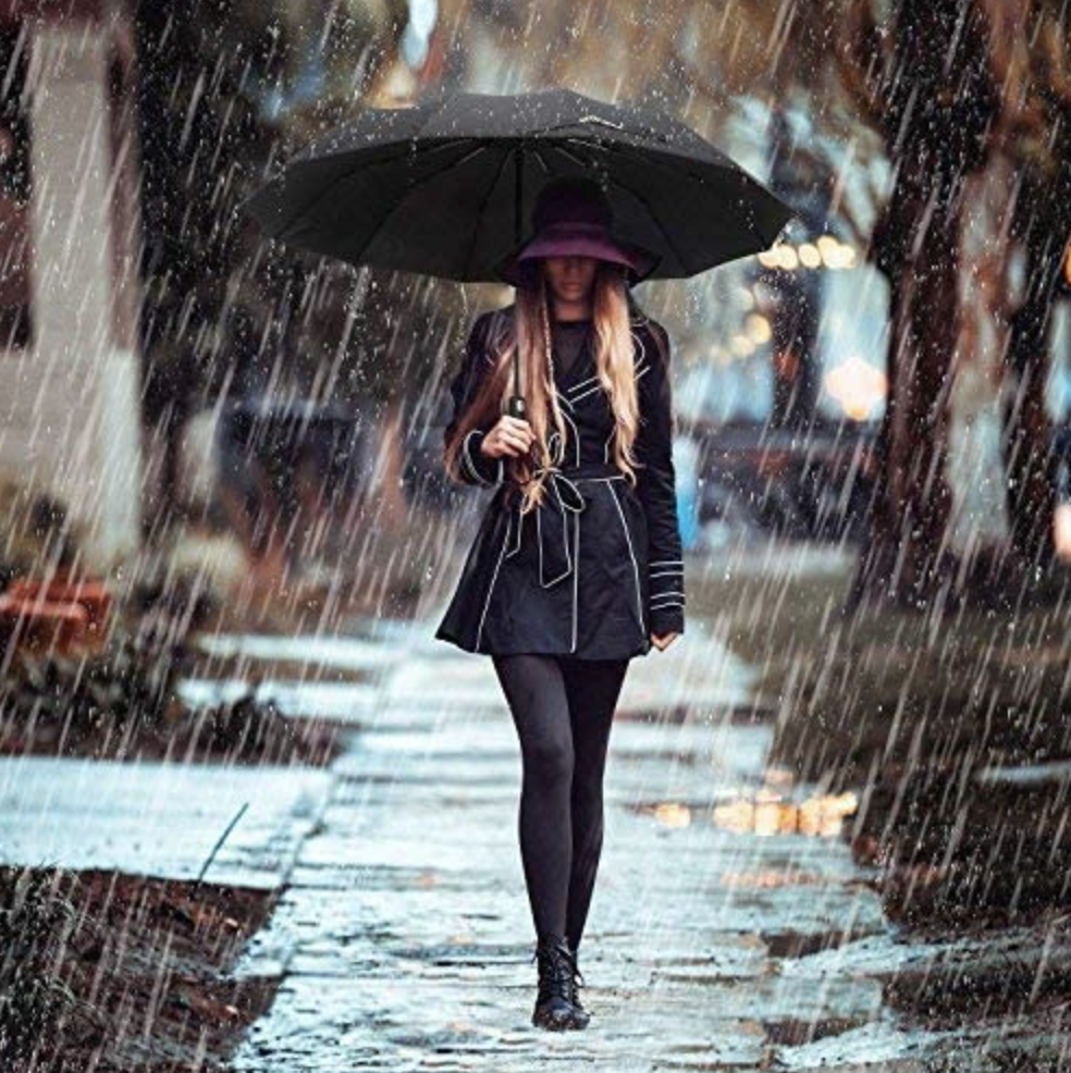 a person walking in the rain while holding the umbrella