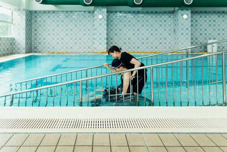 A woman helping a disabled person in the pool