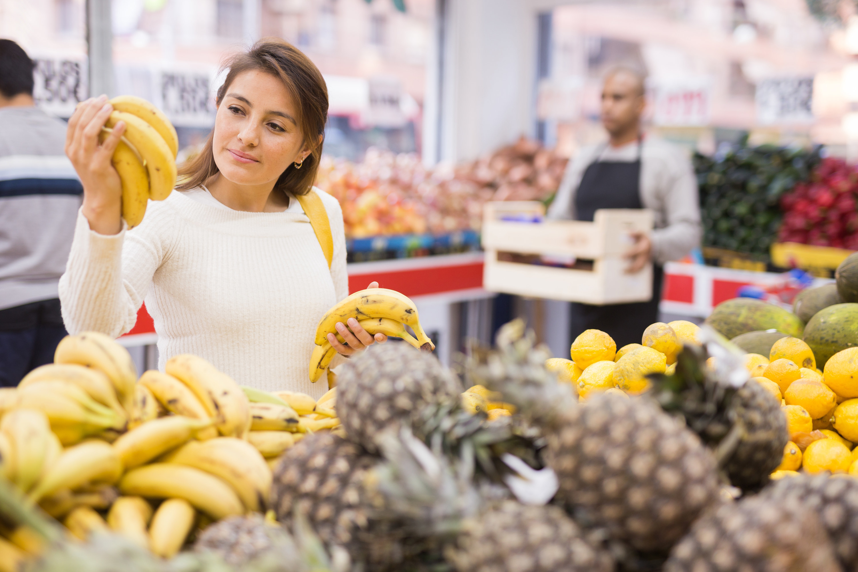 Woman picks ripe bananas at supermarket