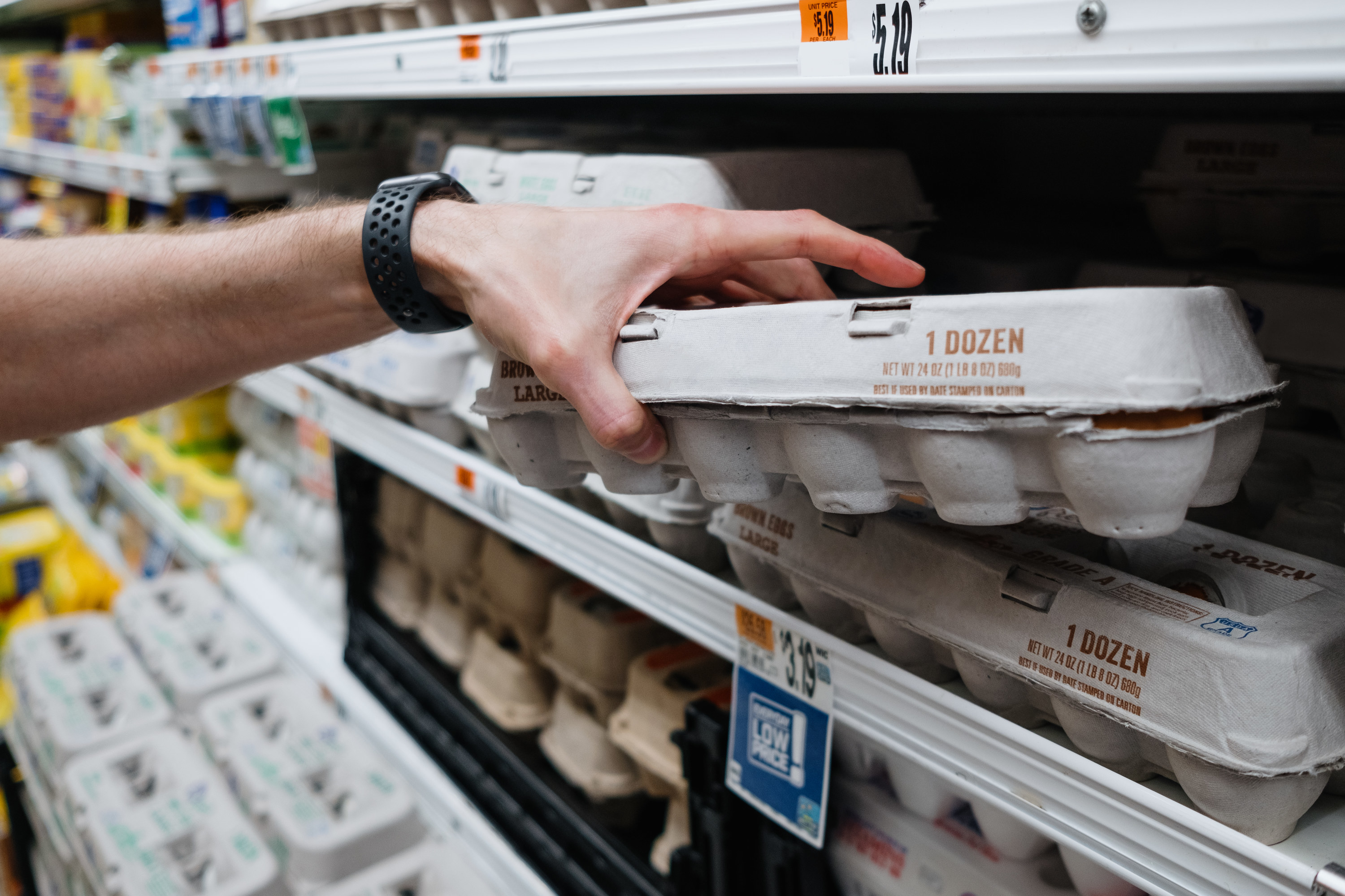 Close-up of person grabbing a carton of eggs at supermarket