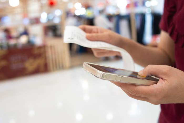 Woman using smart phone scanning QR code on the bill to track spending online