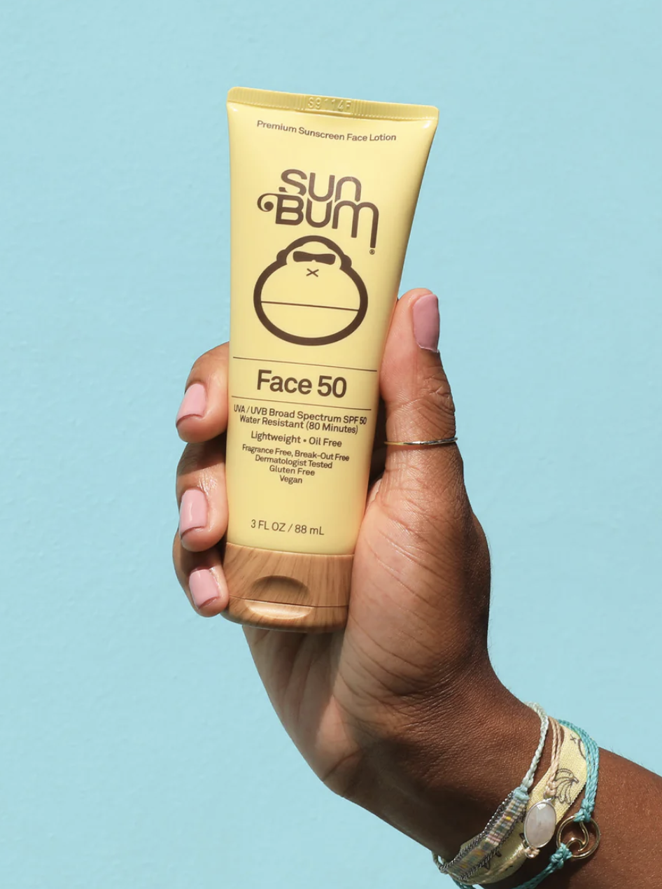 a person holding up the tube of sunscreen in front of a plain bright background