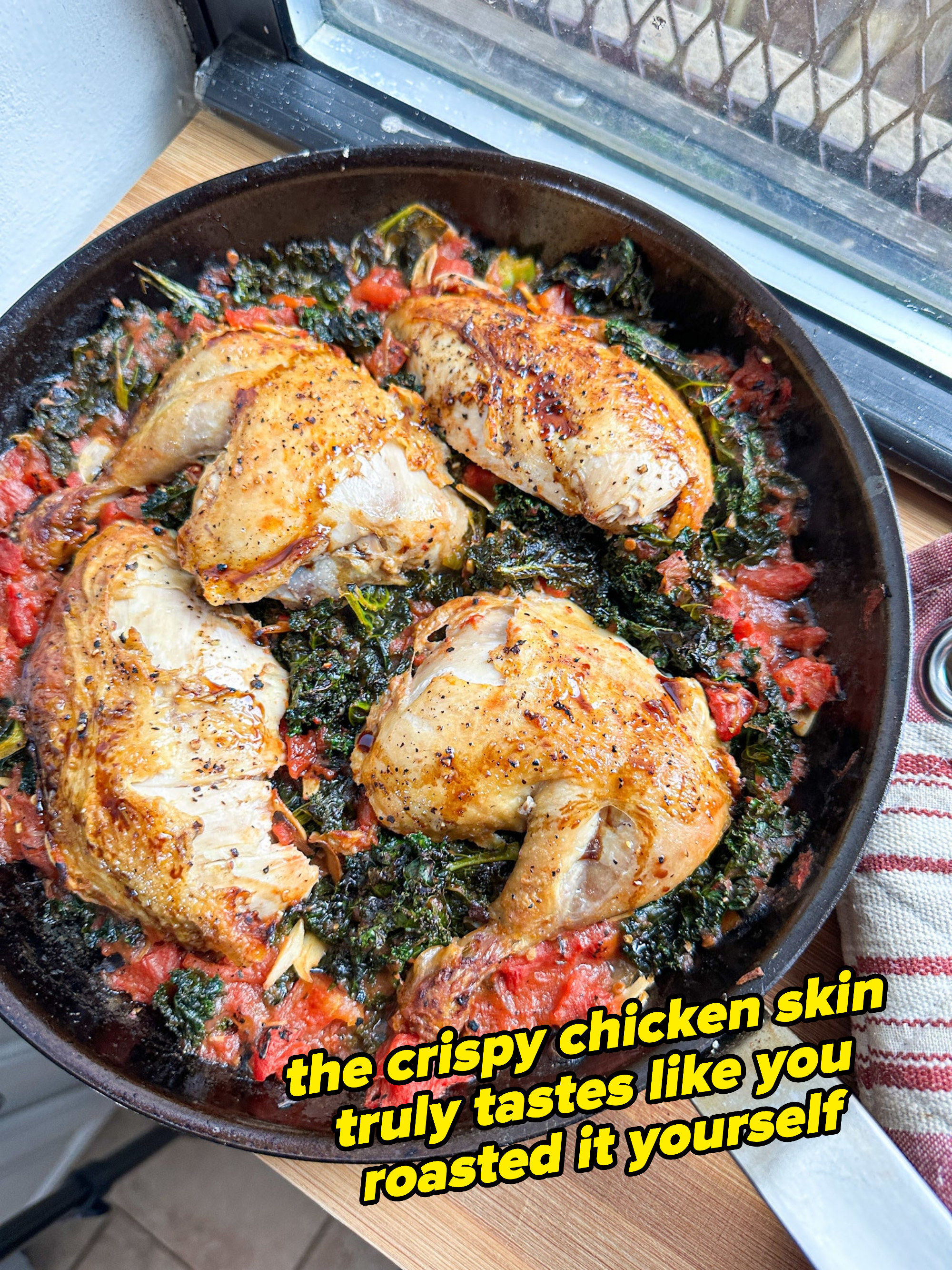 crispy chicken pieces of wilted kale and tomatoes in a skillet, where the crispy chicken skin truly tastes like you roasted it yourself