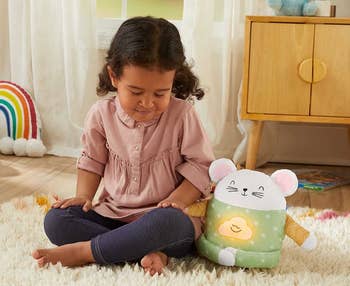 Child model sitting next to white and green meditation mouse toy