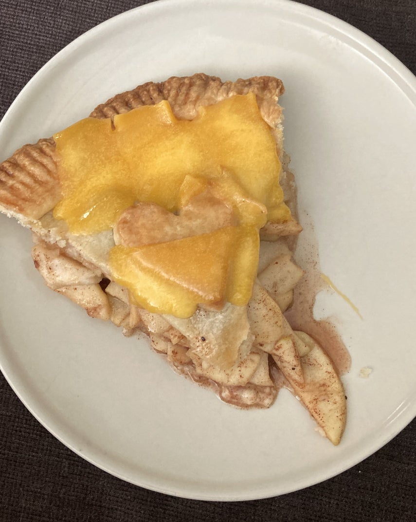 A slice of apple pie with cheddar cheese.