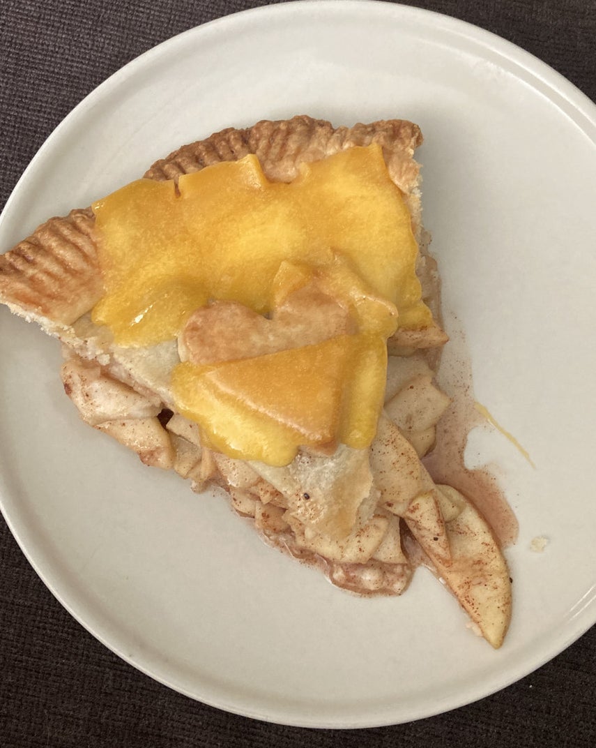 A slice of apple pie with cheddar cheese.
