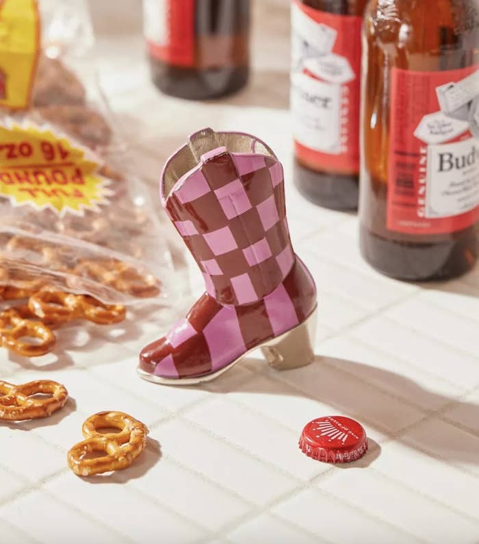 A boot-shaped bottle opener next to a bag of pretzels