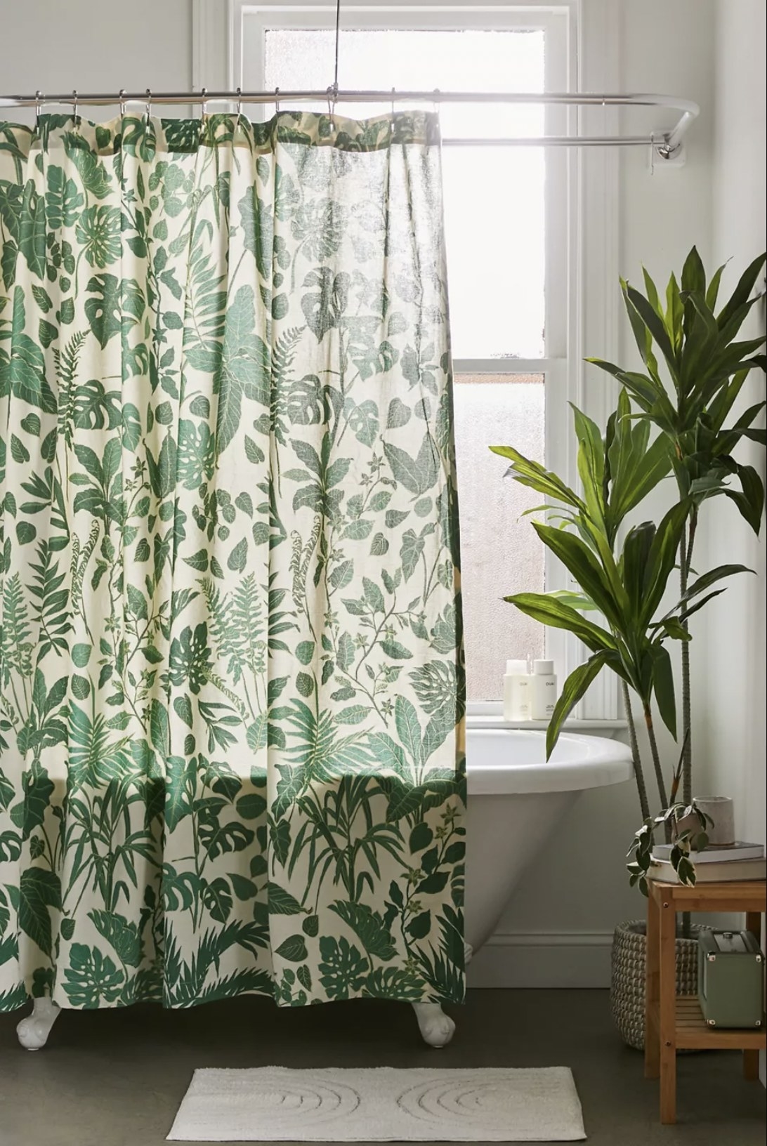 A shower curtain hanging in front of a white bathtub with a jungle print on it