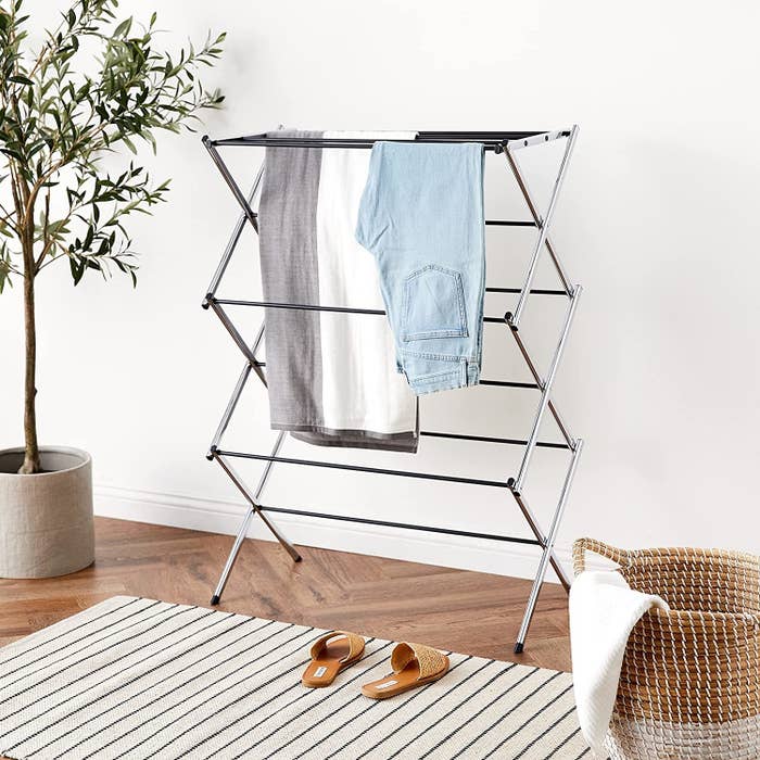 the laundry rack in a living room with a few clothing pieces hanging from it
