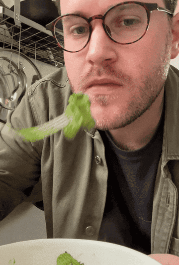 author eating pasta covered in a green sauce and enjoying it