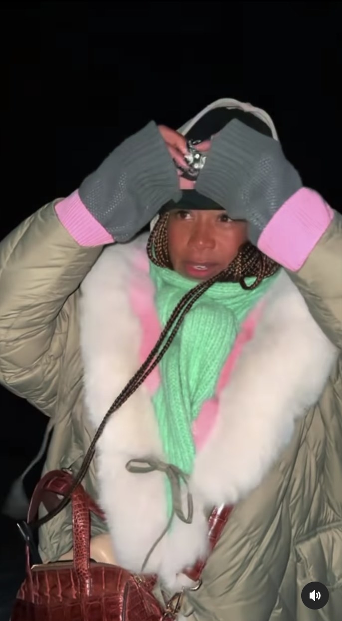 Kelis wears a fur trimmed jacket, large scarf and a light on a headband